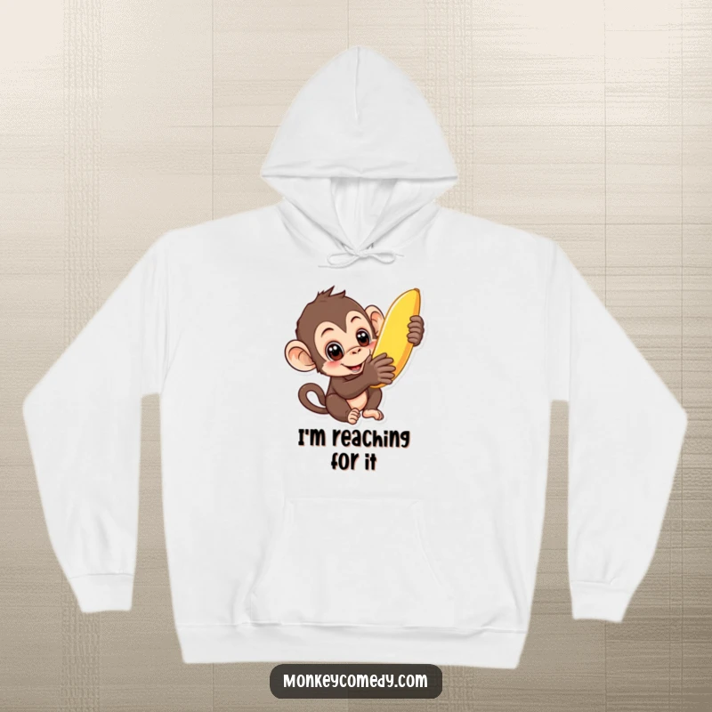 Funny curious monkey hoodie showing a monkey with wide eyes reaching for a banana, perfect for cozy indulgence.