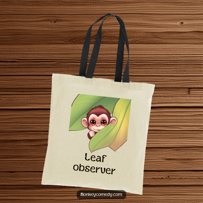 Funny monkey tote bag featuring a small monkey with curious eyes peeking from behind a large, colorful leaf, a humorous and practical accessory.